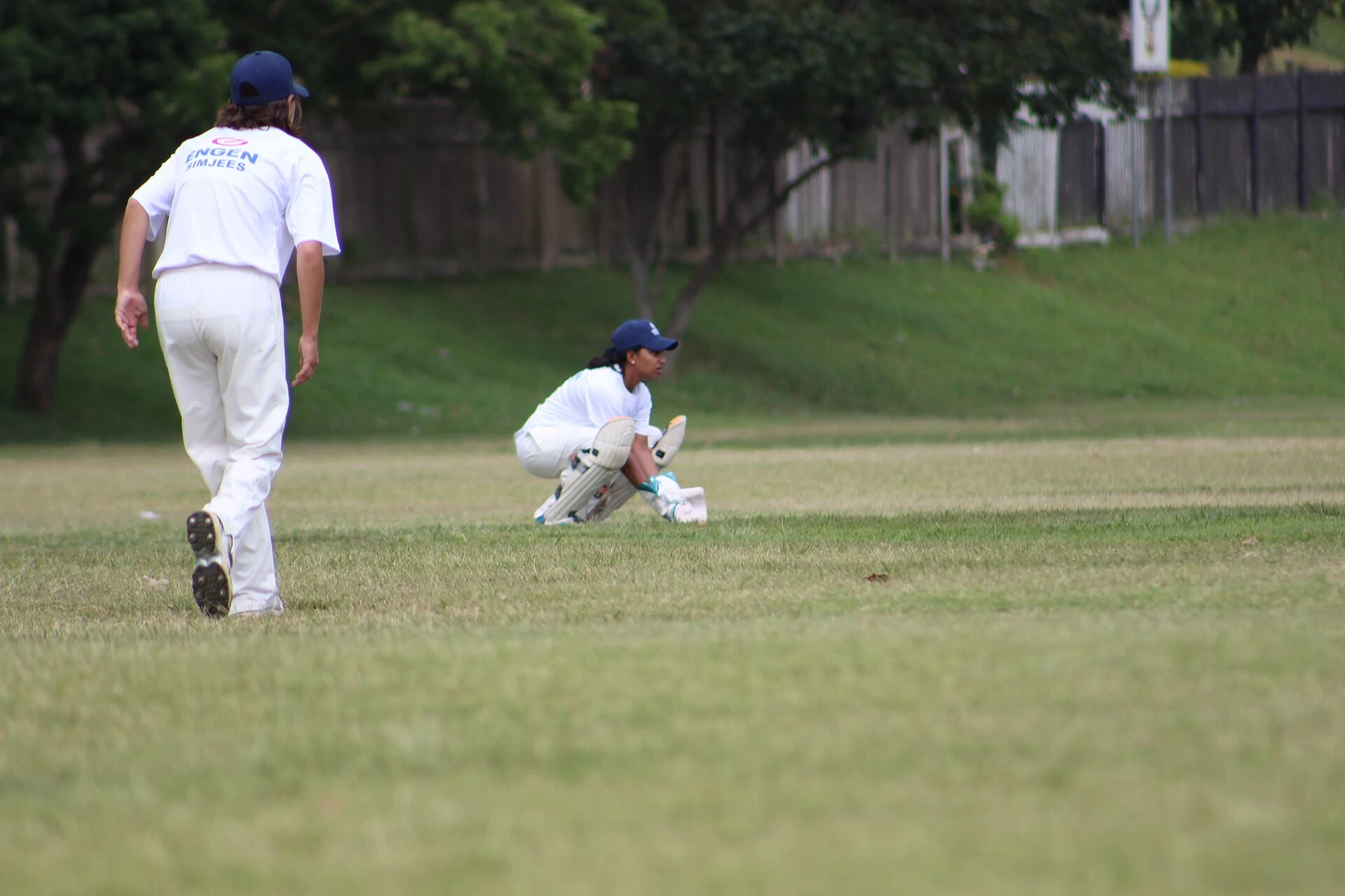 A wicketkeeper prepares behind the stumps during a women's cricket match